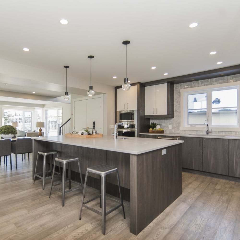 Open-plan kitchen with dark timber cabinetry and metal bar stools